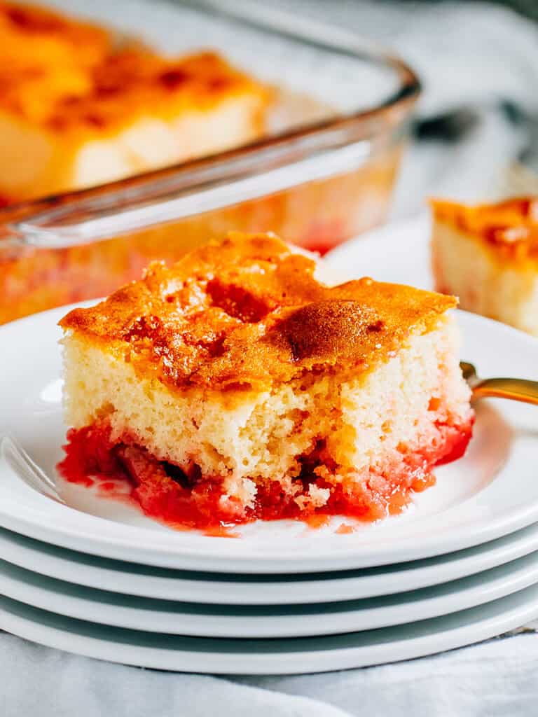 A fun strawberry jello rhubarb cake plated with a forkful missing.