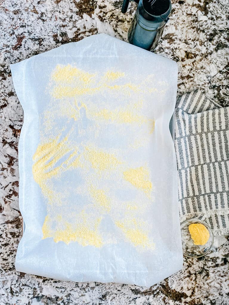 A large rimmed baking sheet covered with parchment paper and sprinkled with corn meal.