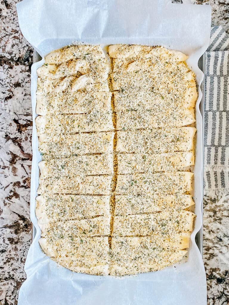 The garlic seasoning sprinkled onto the unbaked butter breadsticks.