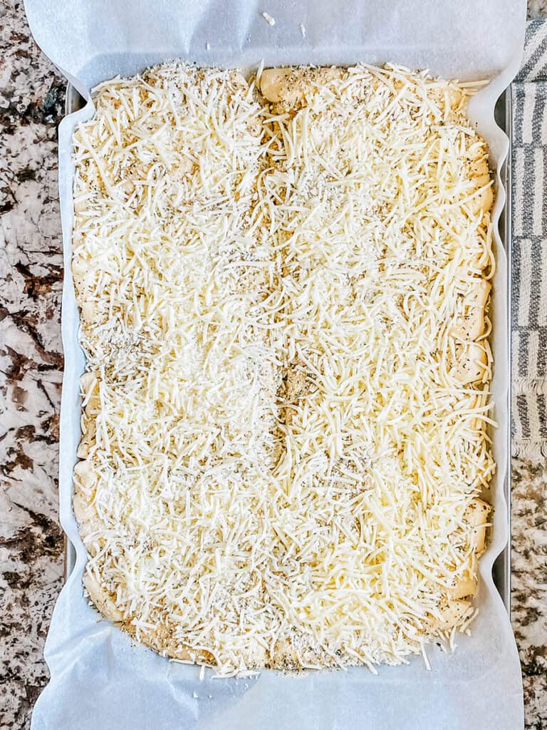 Mozzarella cheese sprinkled on top of the seasoned breadsticks.