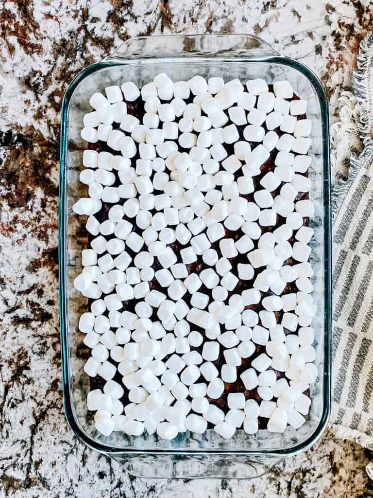 Mini marshmallows on top of a pan of hot freshly baked brownies.