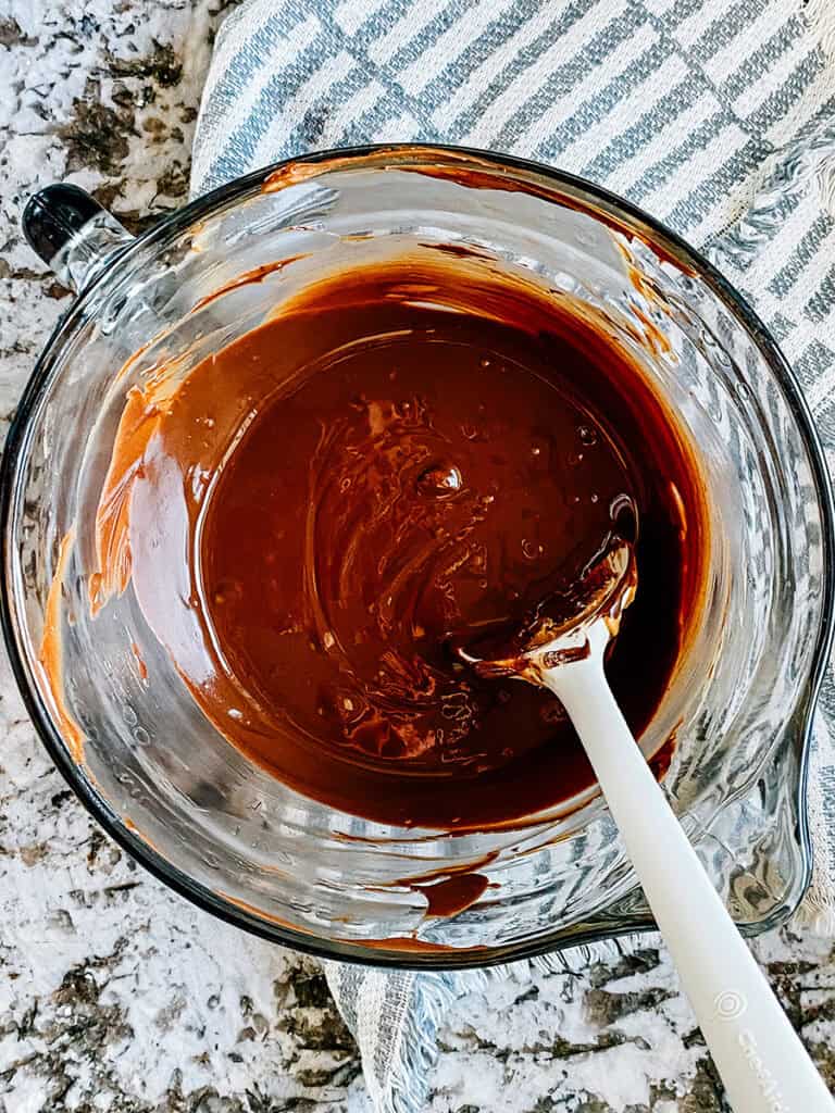 Melted butter, peanut butter, and chocolate in a glass mixing bowl.