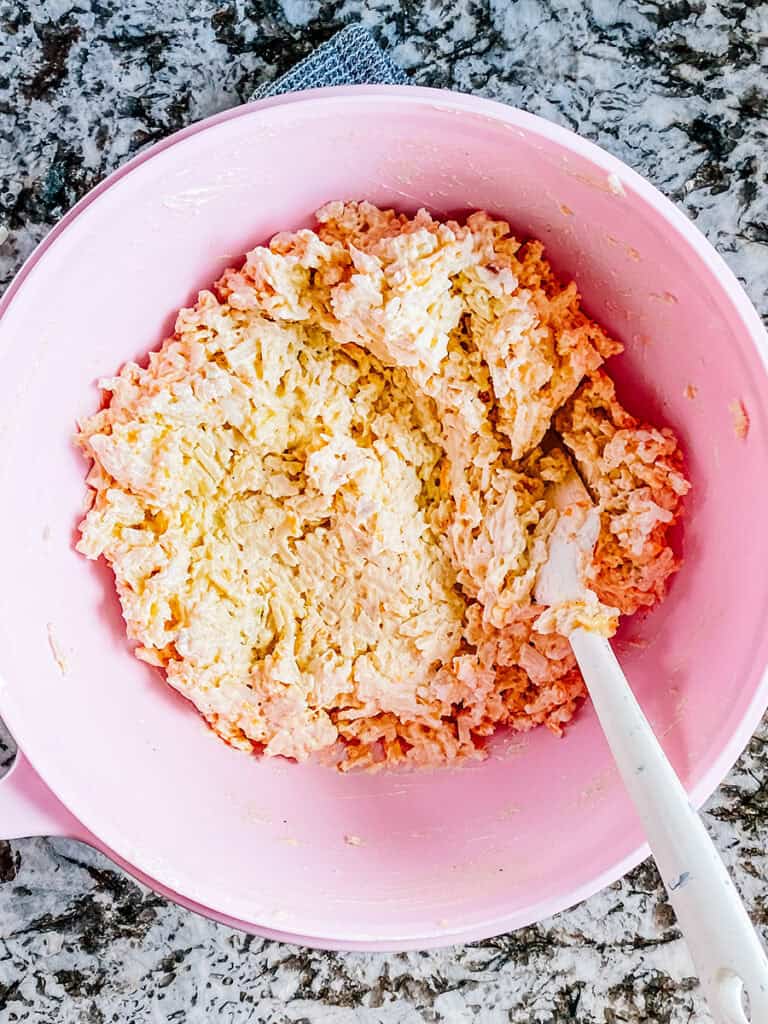 Frozen hash browns, cream of chicken, cream of mushroom, sour cream, cheese, and seasonings mixed in a large bowl.