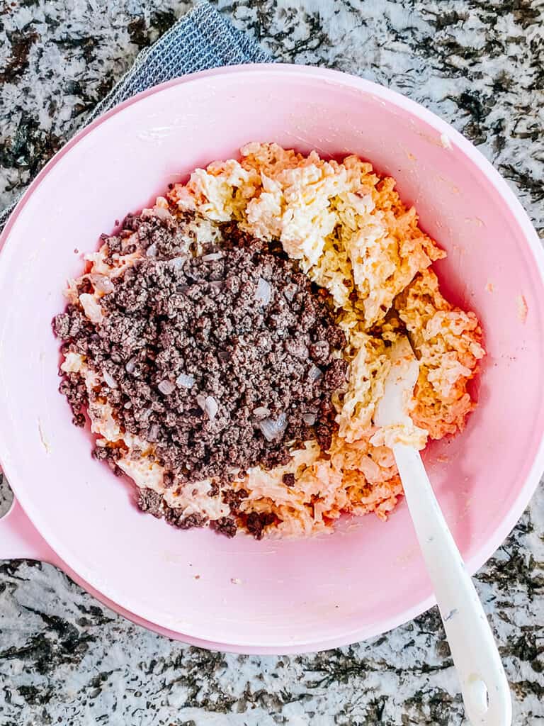 Seasoned browned ground beef with onions and garlic added to the large bowl of creamy frozen hash browns.