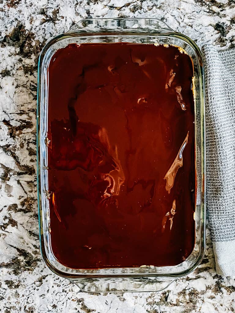 The chocolate sauce spread evenly on top of the peanut butter filling and brownie layers.