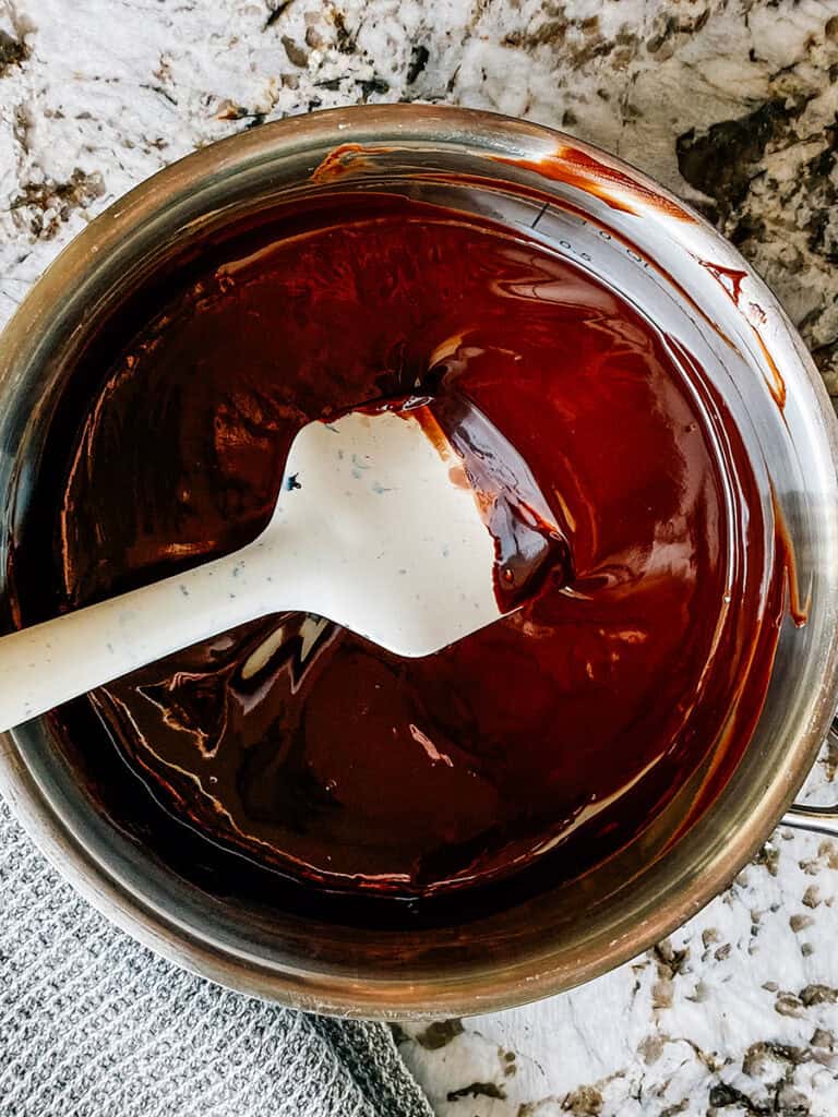 Melted chocolate in a saucepan ready to be spread onto the brownies.