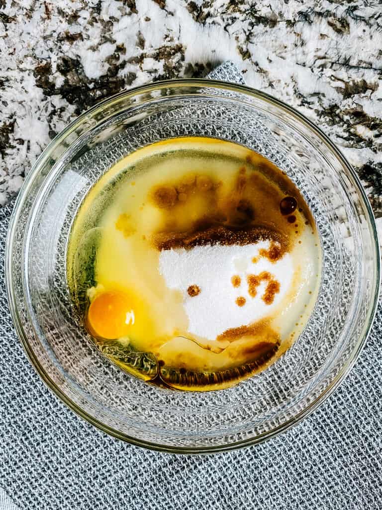 The sugar, oil, vanilla extract, and egg in a mixing bowl.